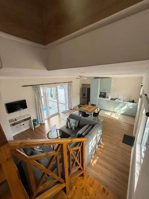 Double-volume living area seen from a mezzanine landing, with dark timber ceiling beams