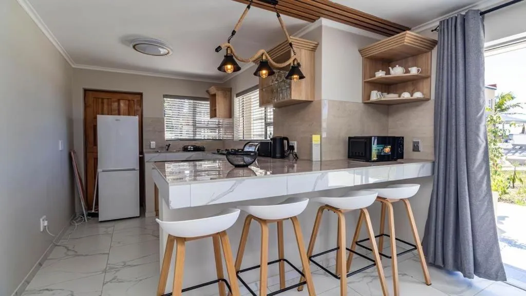 Kitchen with breakfast bar, four stools and pendant lighting over the counter