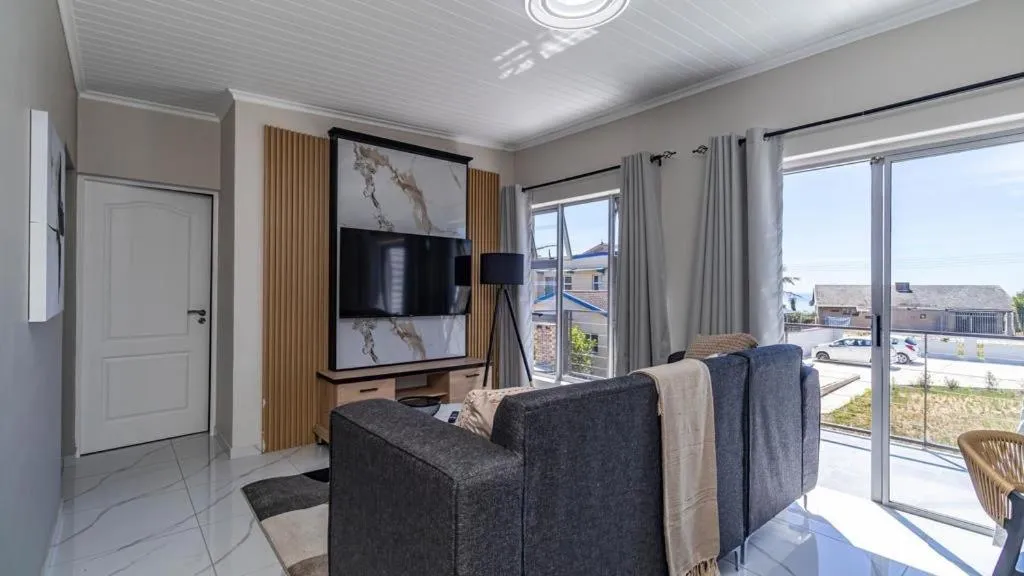 Open-plan living room with sliding doors onto a paved patio and neighbourhood rooftop views