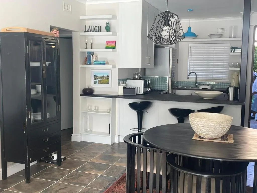 Open kitchen and dining area with black cabinetry, pendant lighting and a round dining table