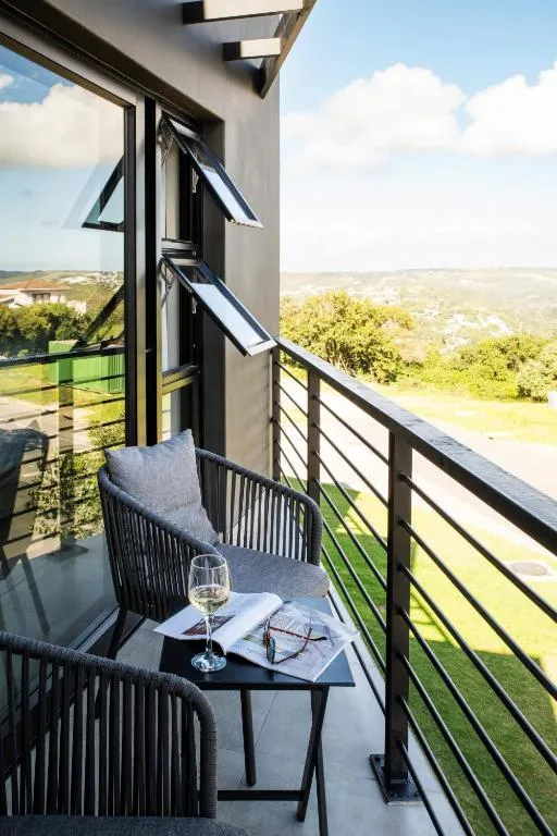 Balcony with two chairs and a wine glass overlooking a green valley