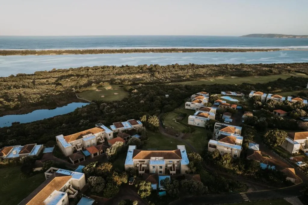 Aerial view of the estate beside the lagoon mouth and open ocean, with golf fairways in between
