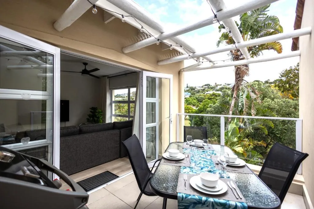 Covered terrace with a built-in braai, string lights and a table set for outdoor dining