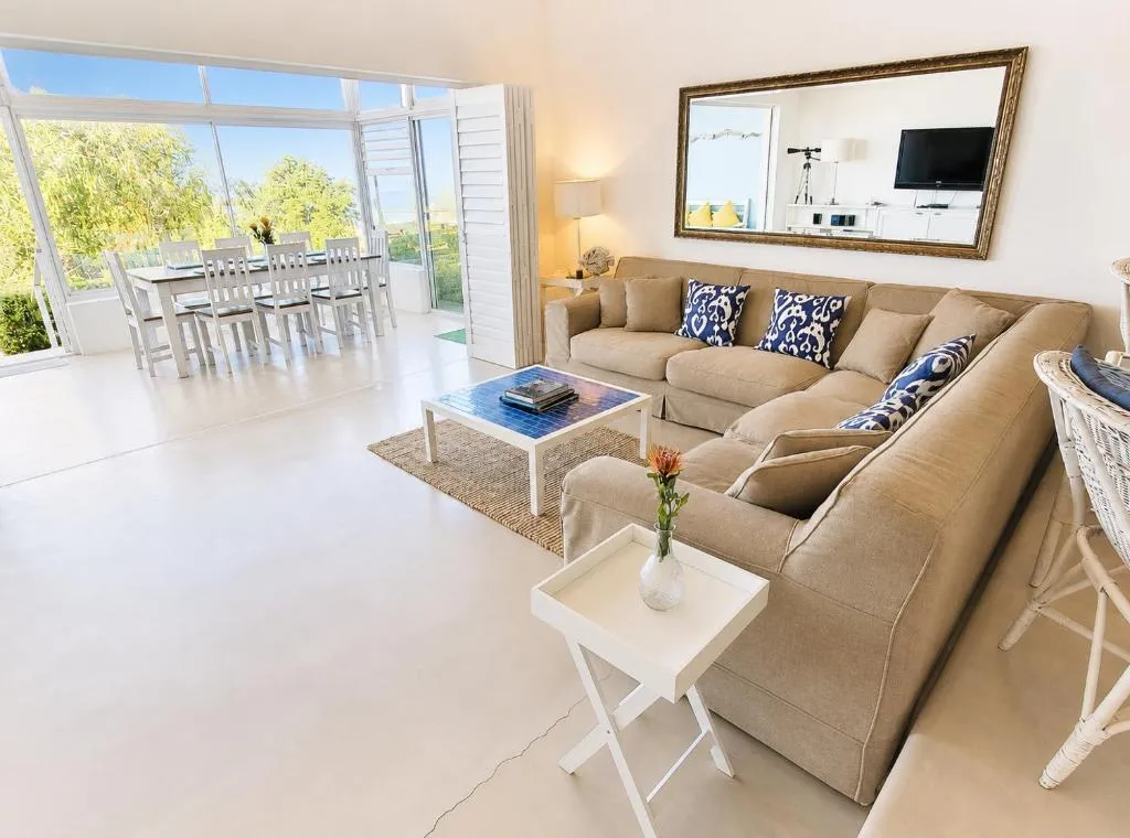 Open-plan lounge with a sectional sofa leading through to the sea-facing dining veranda