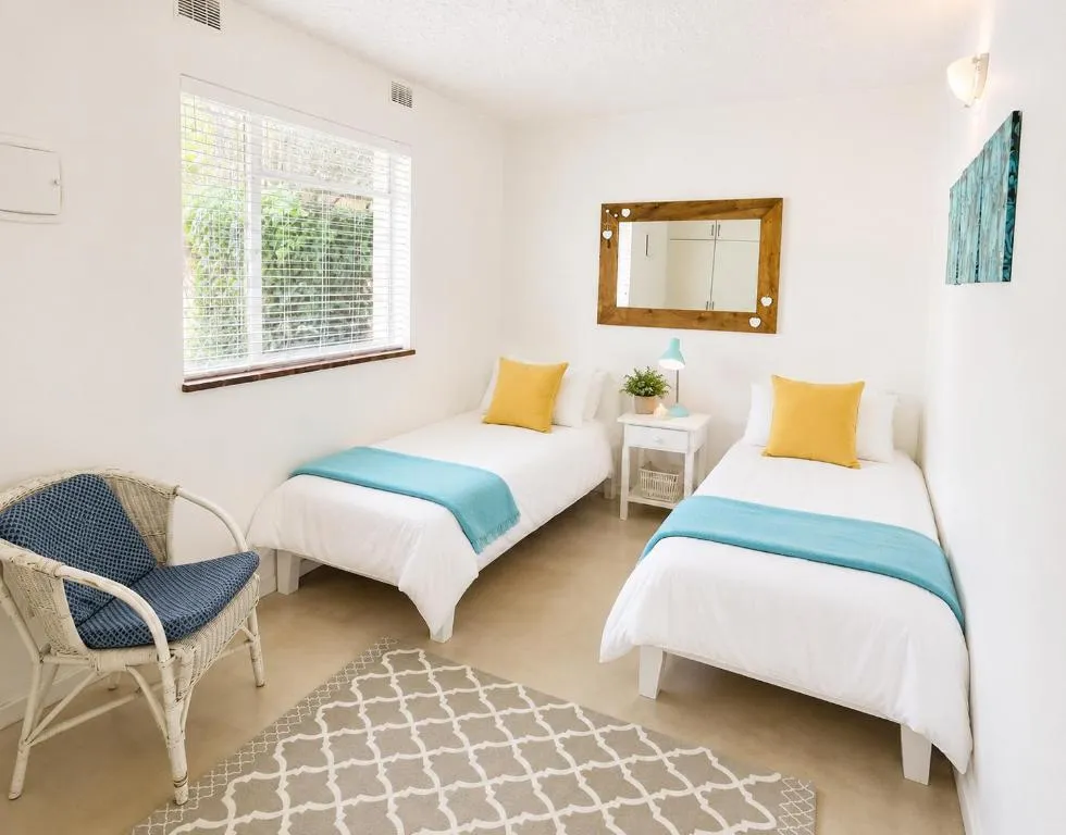 Twin bedroom with two single beds dressed in teal throws and mustard cushions