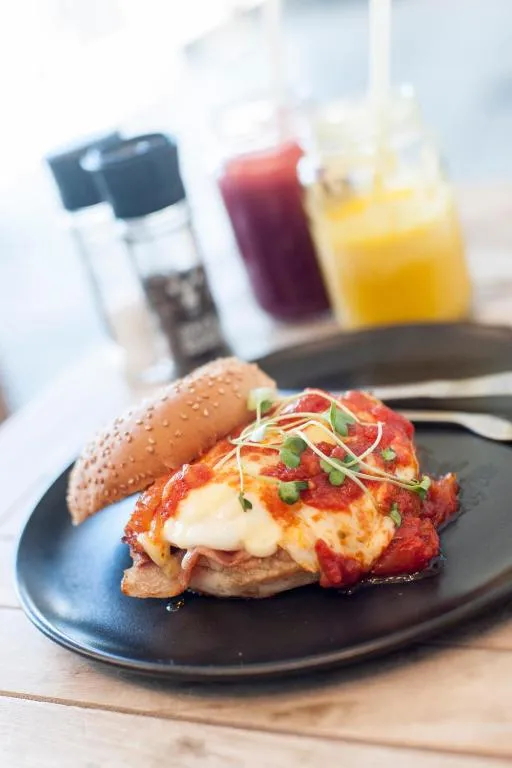 Toasted breakfast roll topped with melted cheese and tomato, served with fresh juices
