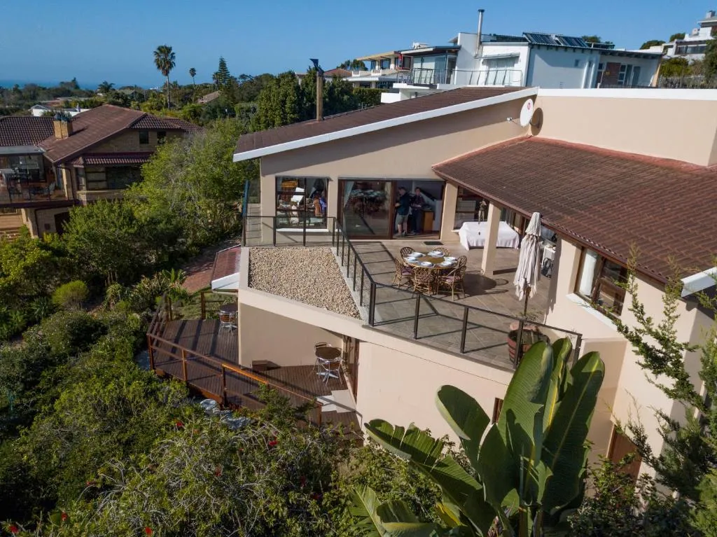 Aerial view of the tiled-roof guesthouse with a paved terrace, dining table and garden banana plants