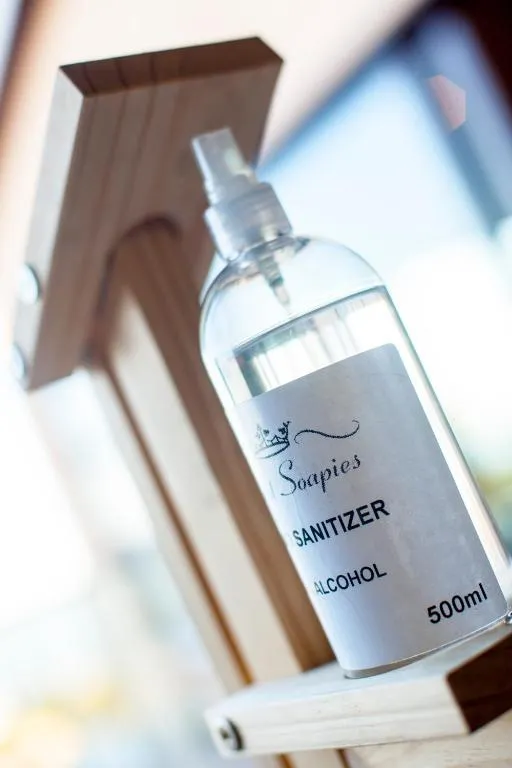 Bottle of alcohol-based hand sanitizer standing on a wooden shelf