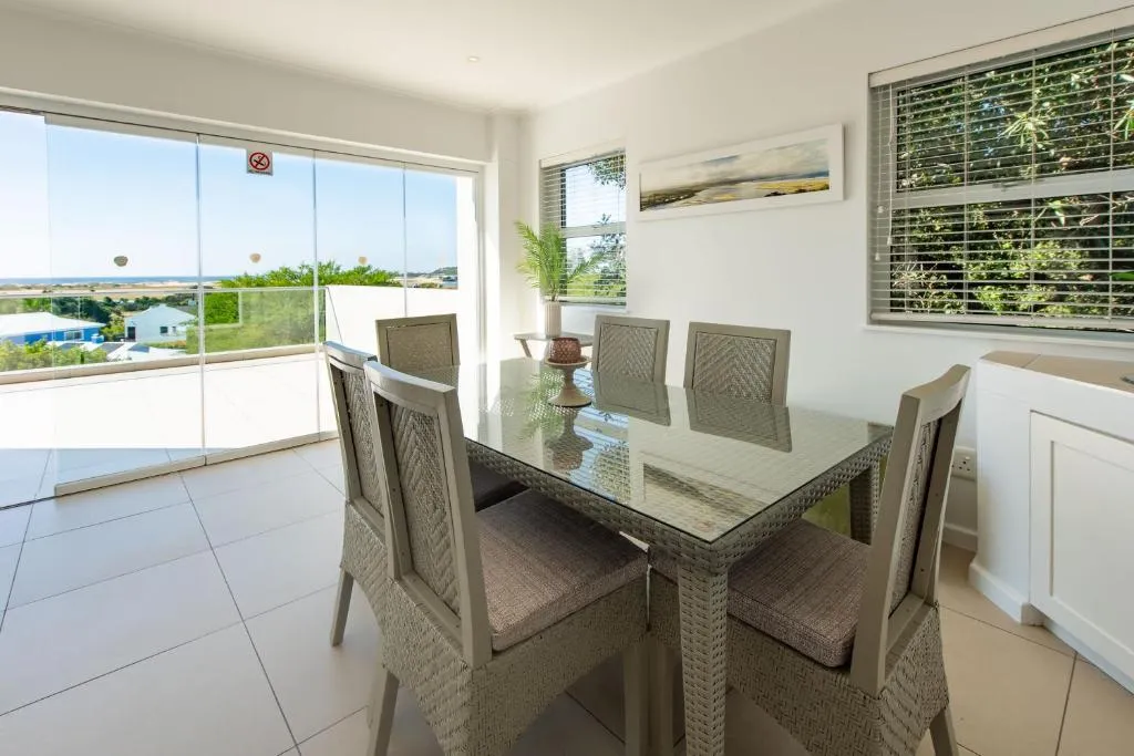 Dining table beside floor-to-ceiling sliding doors opening onto a sea-view terrace