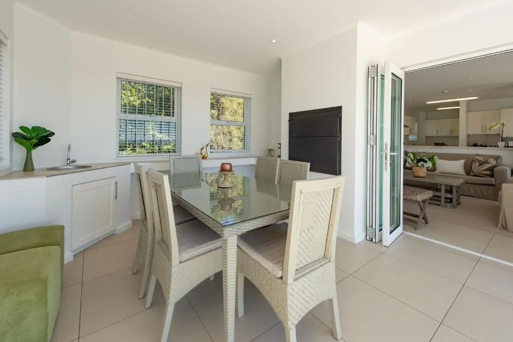 Open-plan dining and lounge area with woven rattan chairs opening to the kitchen