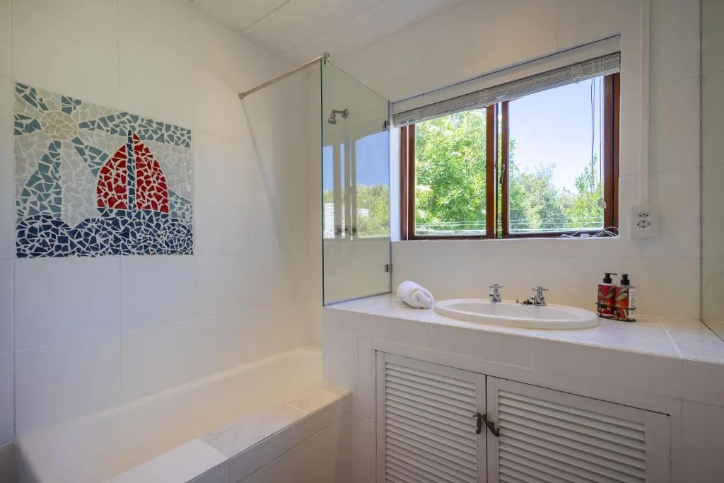 Bathroom with tub, sailboat mosaic tile art and a garden-facing window