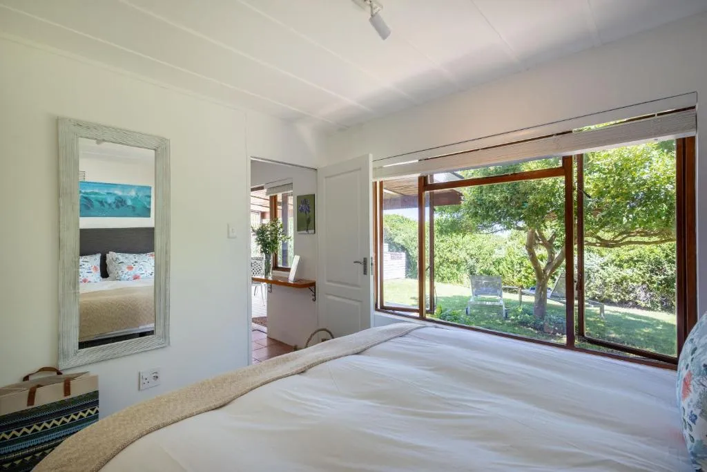 Bedroom with sliding glass doors opening onto a tree-shaded garden lawn