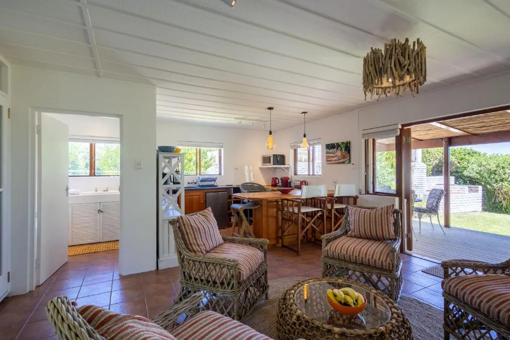 Open-plan lounge with wicker armchairs, dining table and kitchenette beyond