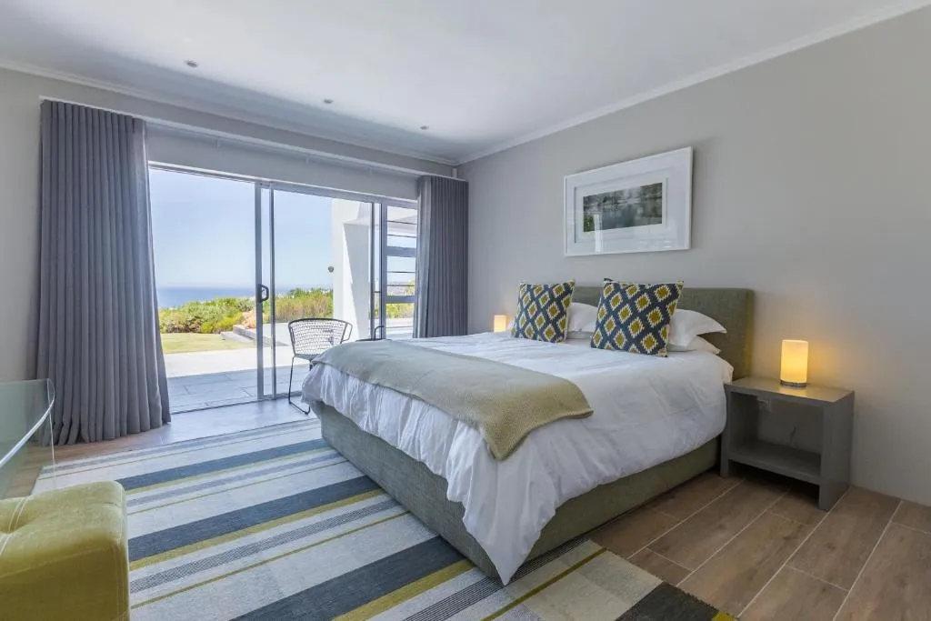 Main bedroom with sliding doors onto a private patio overlooking the garden and coastline