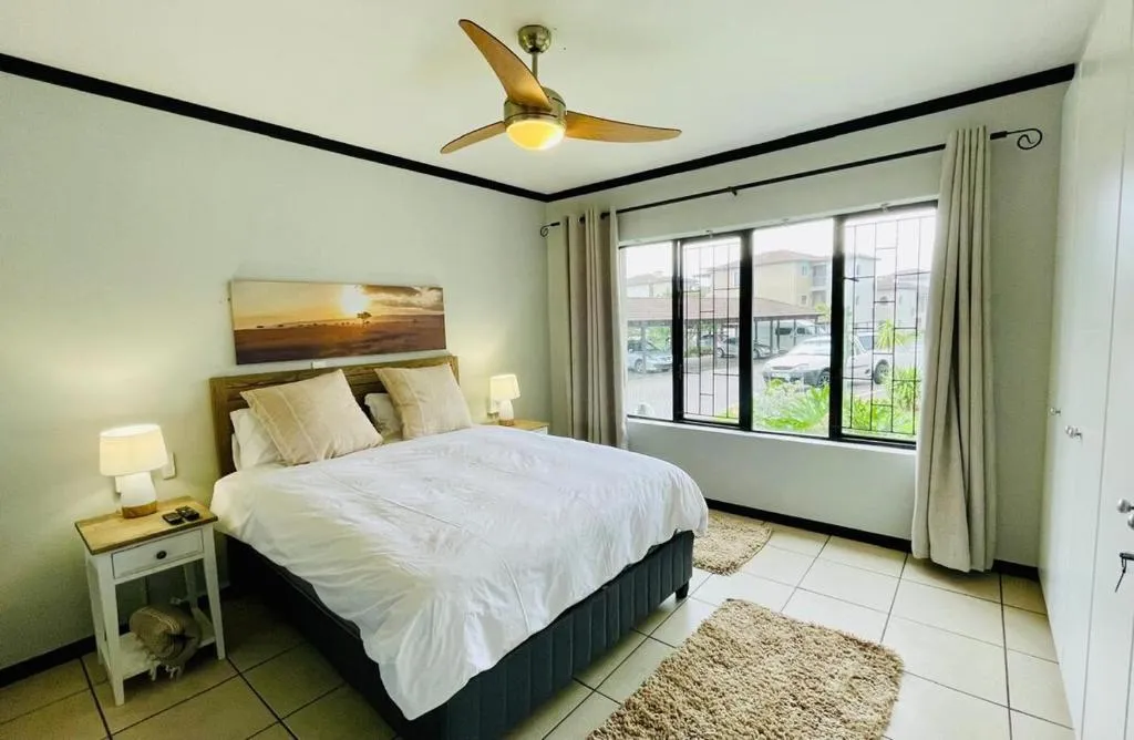 Bedroom with a sunset canvas above the bed and a window overlooking the parking area