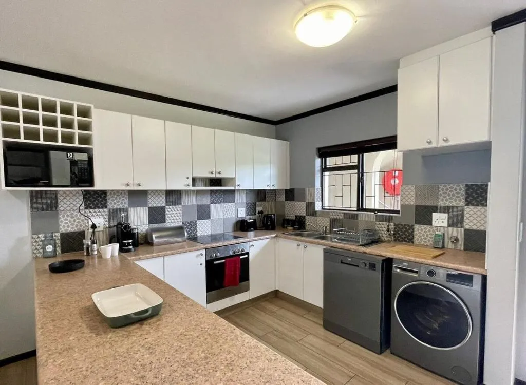 Kitchen with white cabinetry, black countertops and a burglar-barred window