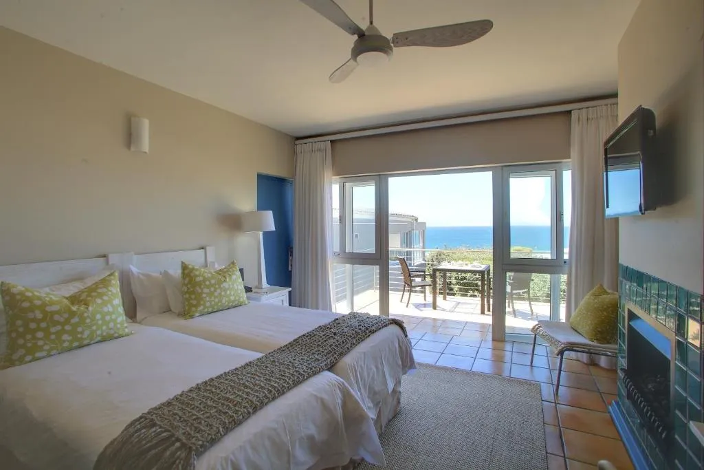 Twin bed suite with a private balcony and uninterrupted ocean view through sliding doors