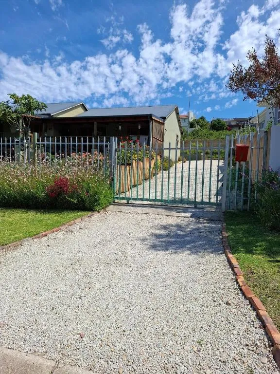 Gravel driveway and garden gate framed by flowering borders at the property entrance