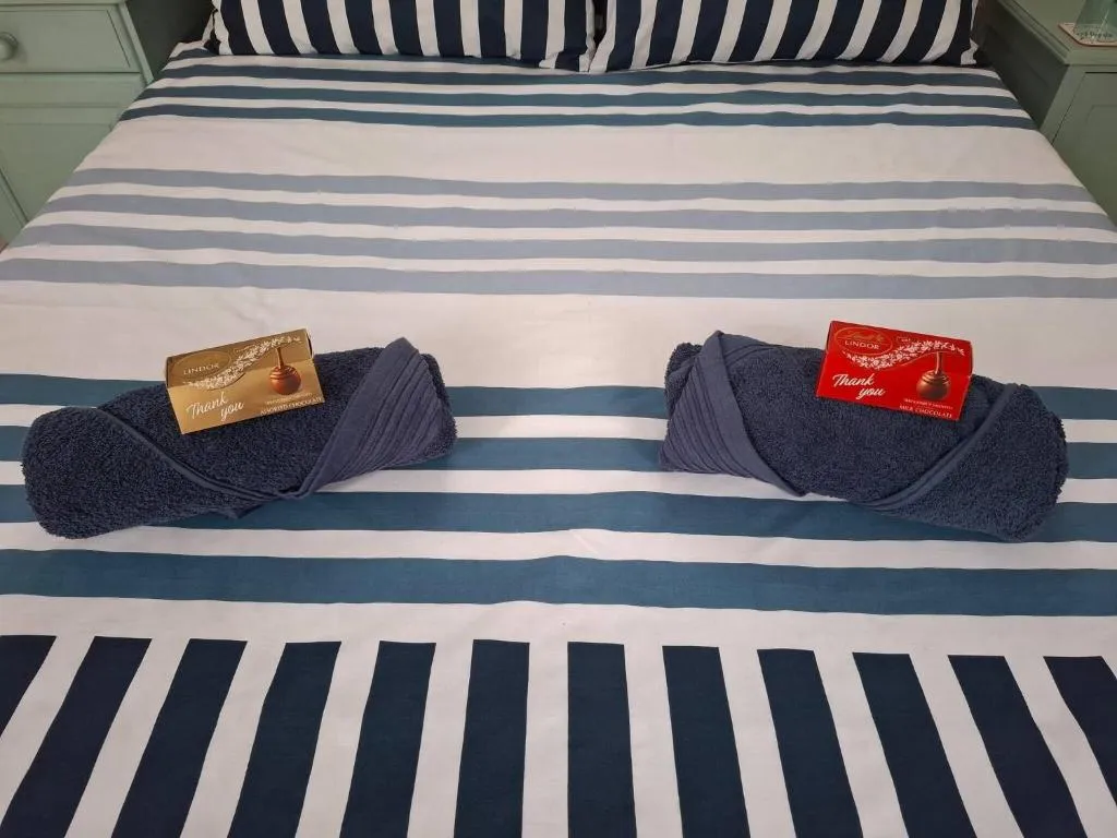 Close-up of folded towels and welcome chocolates styled on the striped bedspread