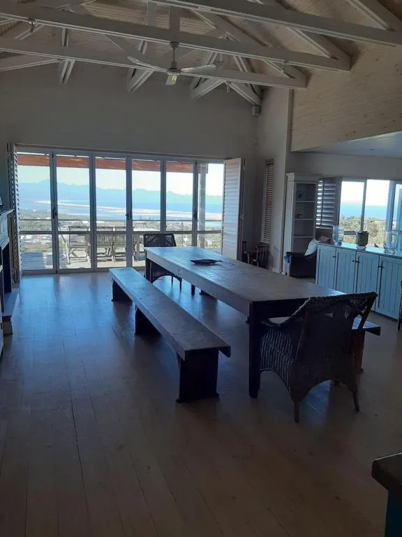 Vaulted-ceiling dining area with a long wooden table and doors onto the view