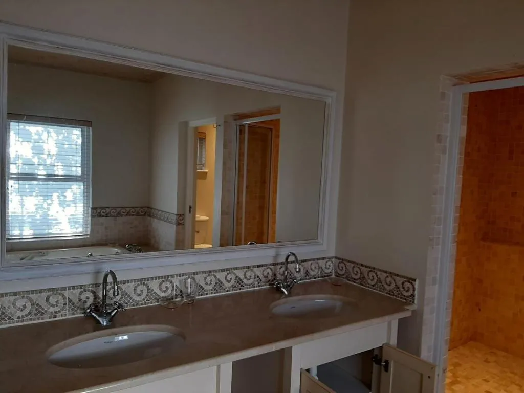 En-suite bathroom with a double vanity, wall mirror and a walk-in tiled shower