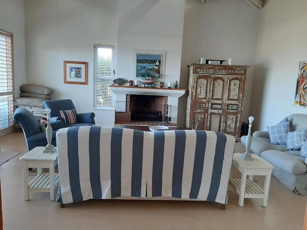 Living room with a brick fireplace, striped sofa and a rustic painted cabinet