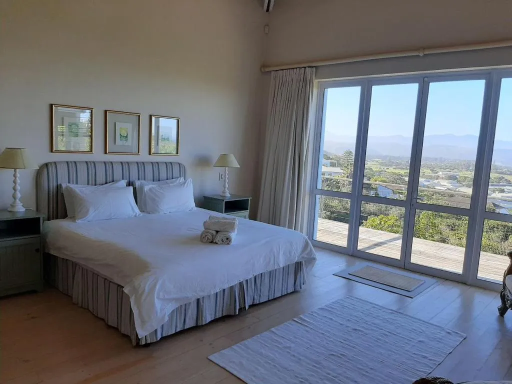 Bedroom with a king bed, glass sliding doors and a balcony view over the hills