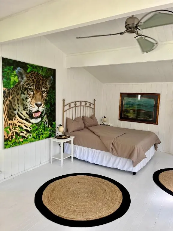 Bedroom with a wrought-iron bed frame, a jungle-cat canvas, and a round jute rug