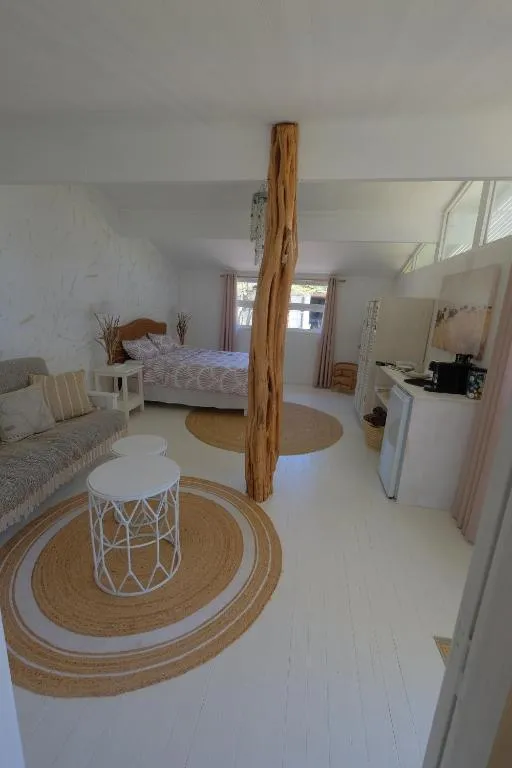 Studio interior with a striped sofa, round jute rugs and a rustic driftwood pole beside the bed