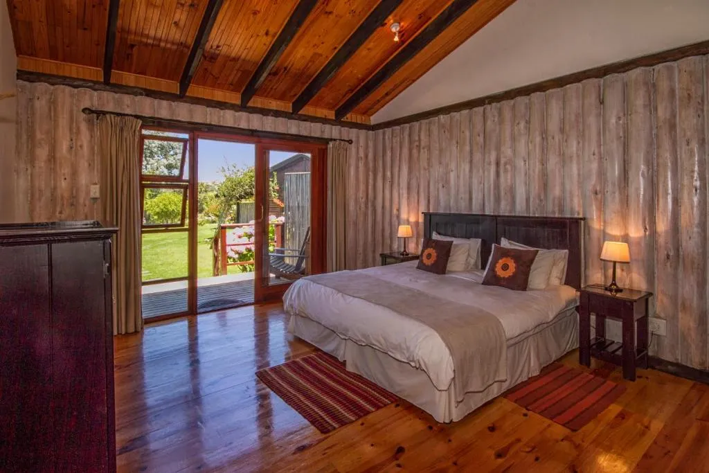 Timber-clad bedroom with a beamed ceiling and sliding doors onto a garden patio