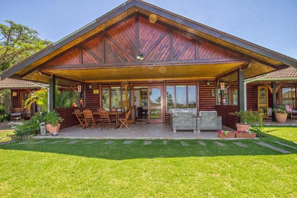 Covered veranda of the main lodge with an outdoor dining table, wicker seating and garden view