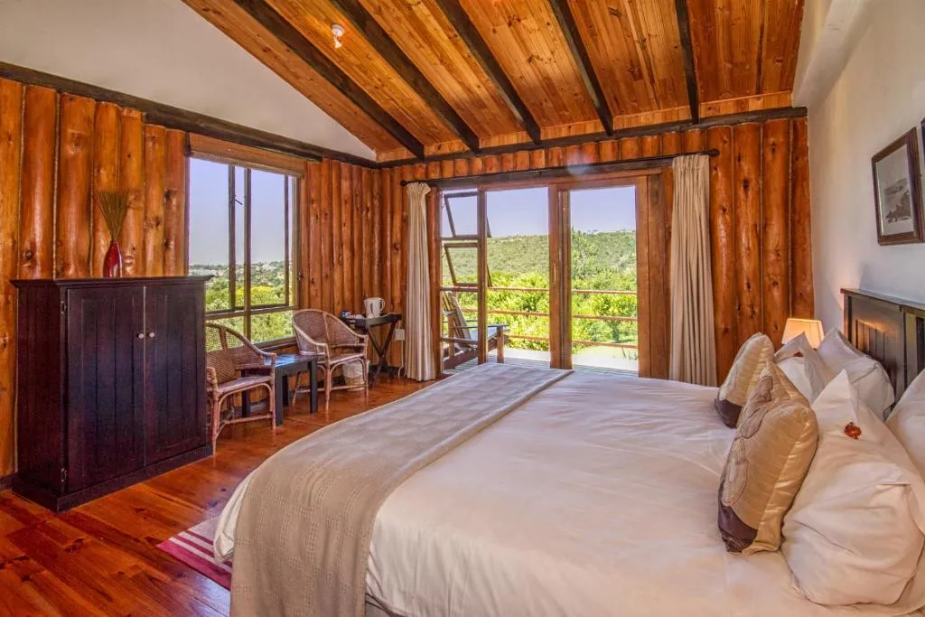 Log-cabin bedroom with a vaulted beamed ceiling, sliding doors and a private balcony over the valley