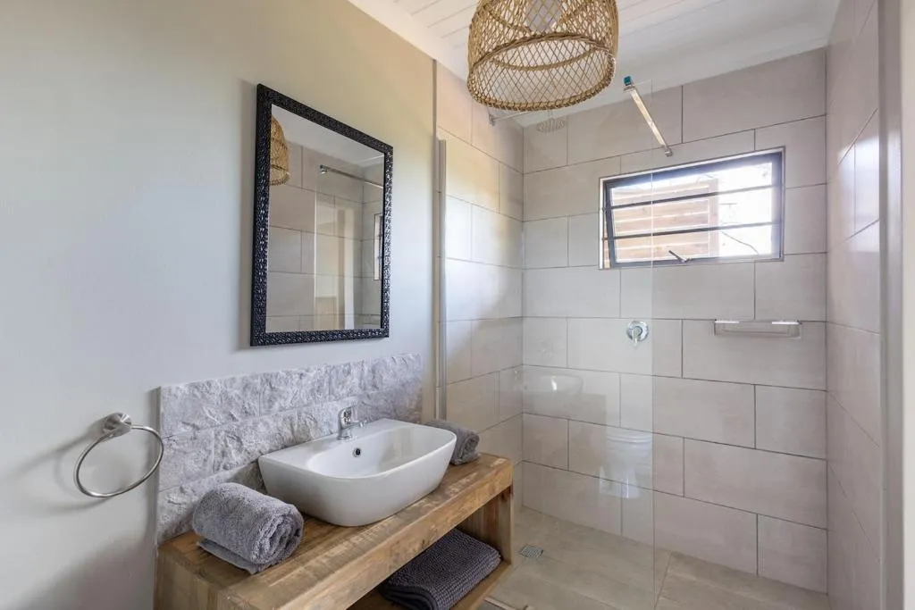 Bathroom with vessel sink on a wood-topped vanity and glass-walled shower