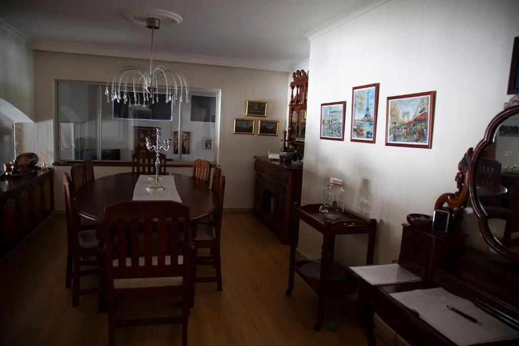 Dining room with a round table, crystal chandelier and framed European cityscape prints