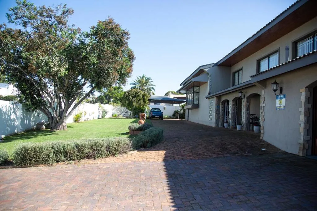 Side view of the house across a lawned garden with a brick driveway and parked car