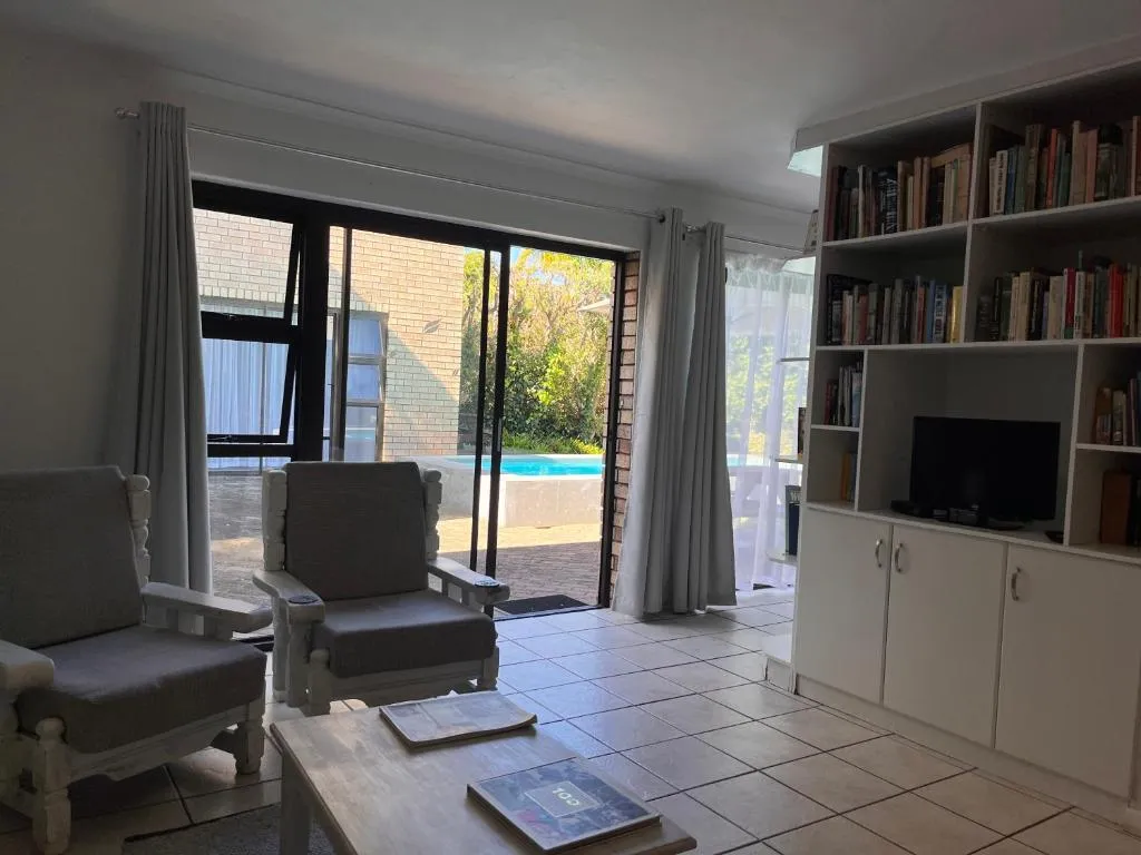 Living room with built-in bookshelf, TV unit and sliding doors onto the pool deck