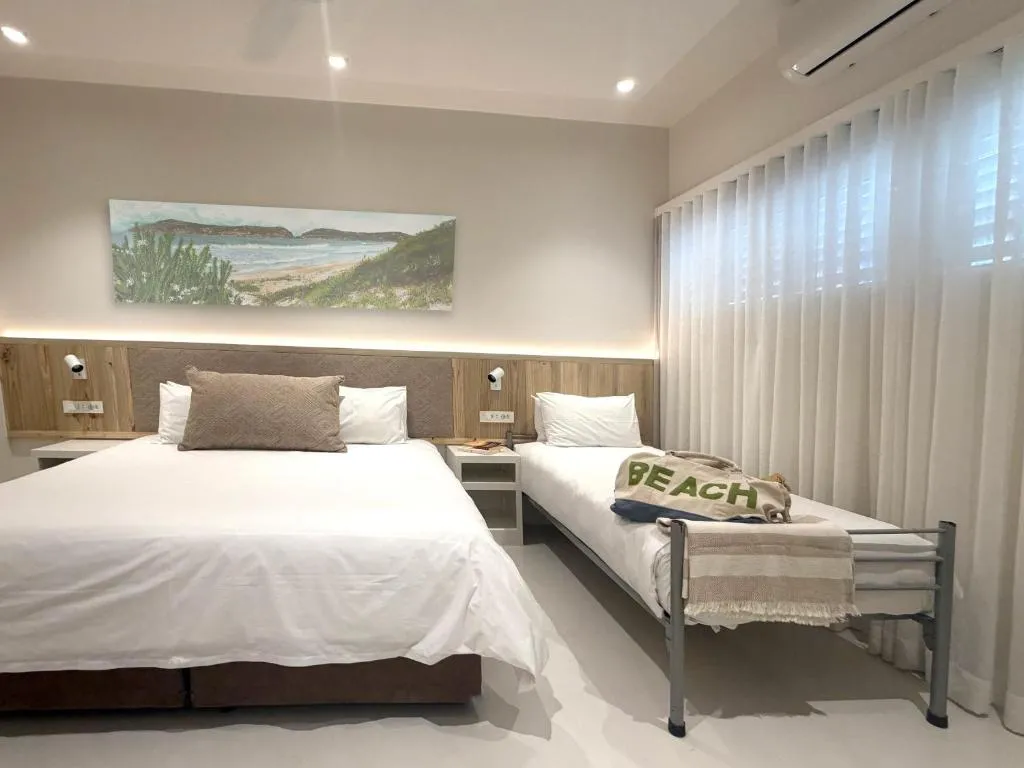 Twin/double room with a wall-mounted air conditioner and beach-themed art