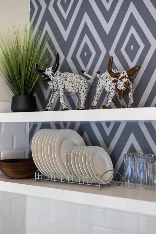 Open shelf styled with beaded animal ornaments, plates and glassware