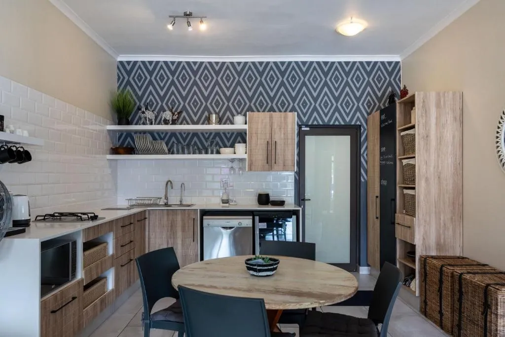 Compact kitchenette with a patterned tile splashback, gas hob and open shelving