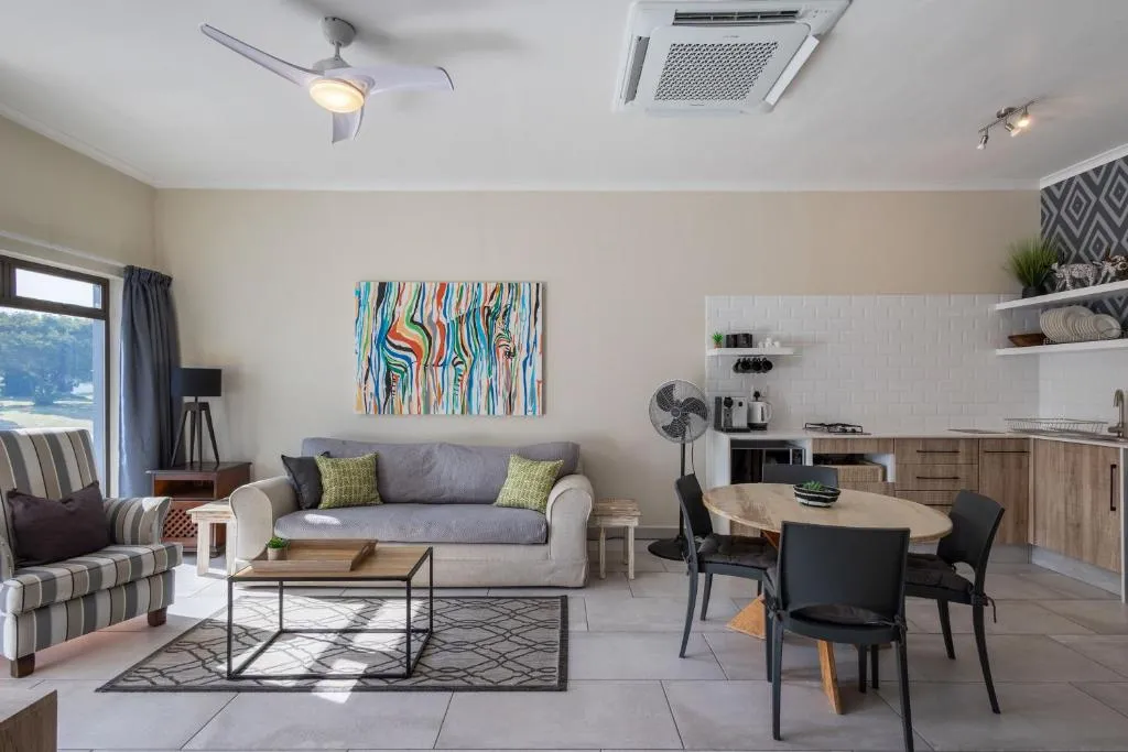 Open-plan lounge and dining area with a ceiling air-conditioning unit and kitchenette beyond