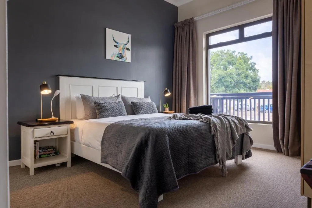 Main bedroom with a dark feature wall, built-in headboard and sliding doors onto a balcony