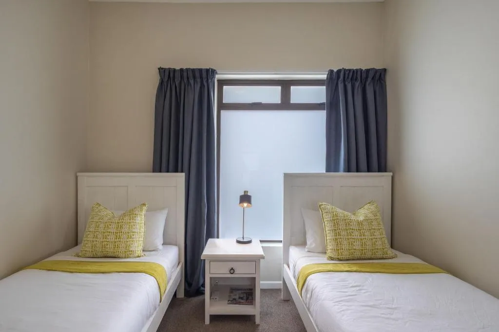 Twin bedroom with two single beds and mustard-yellow throw blankets