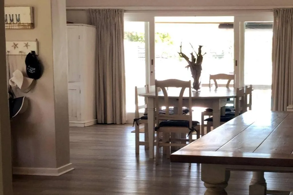 Open-plan dining area with a long wooden table and views to the covered patio