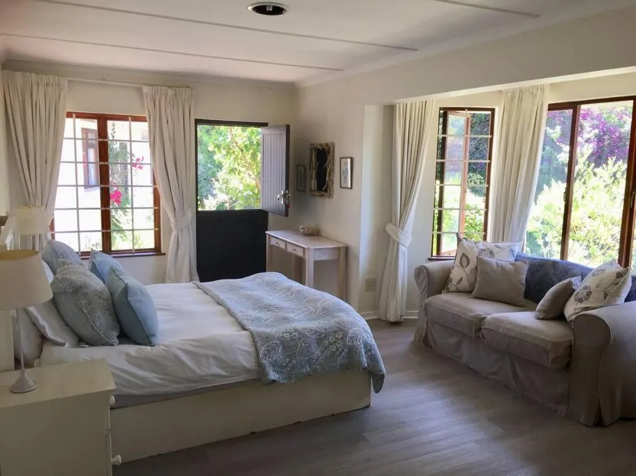 Guest bedroom with a separate sitting area and timber windows onto greenery