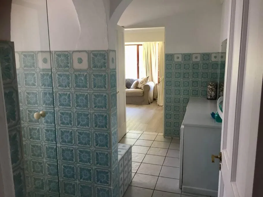 Green patterned-tile passage with built-in cupboards linking the bedroom to the lounge