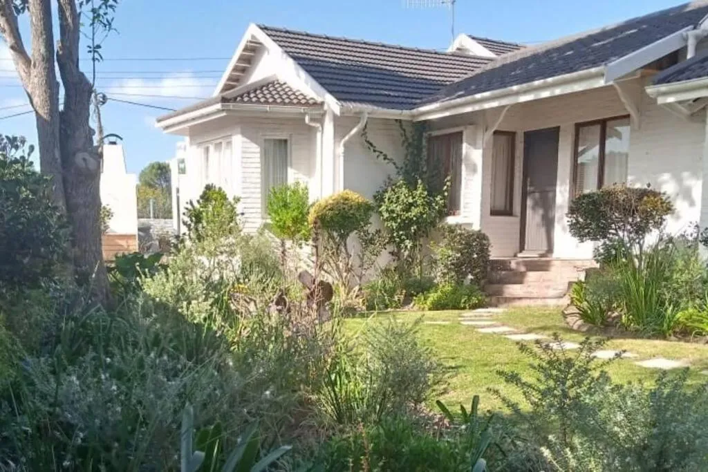 White cottage-style holiday home with tiled roof and a landscaped front garden path
