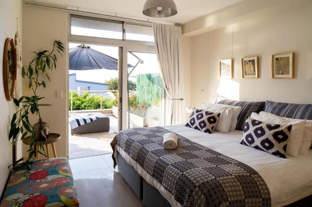 Bedroom with patterned cushions and sliding doors onto a furnished balcony