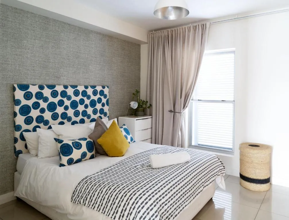 Bedroom with a circle-print headboard, mustard cushion and a woven laundry hamper