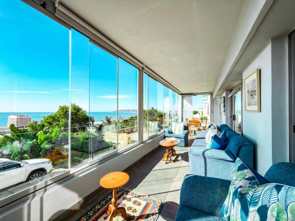 Glassed-in sunroom lounge with sofas and floor-to-ceiling windows over the ocean