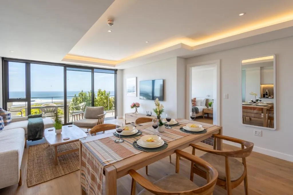 Open-plan dining area set for a meal with sea views through the adjoining living room's glass doors